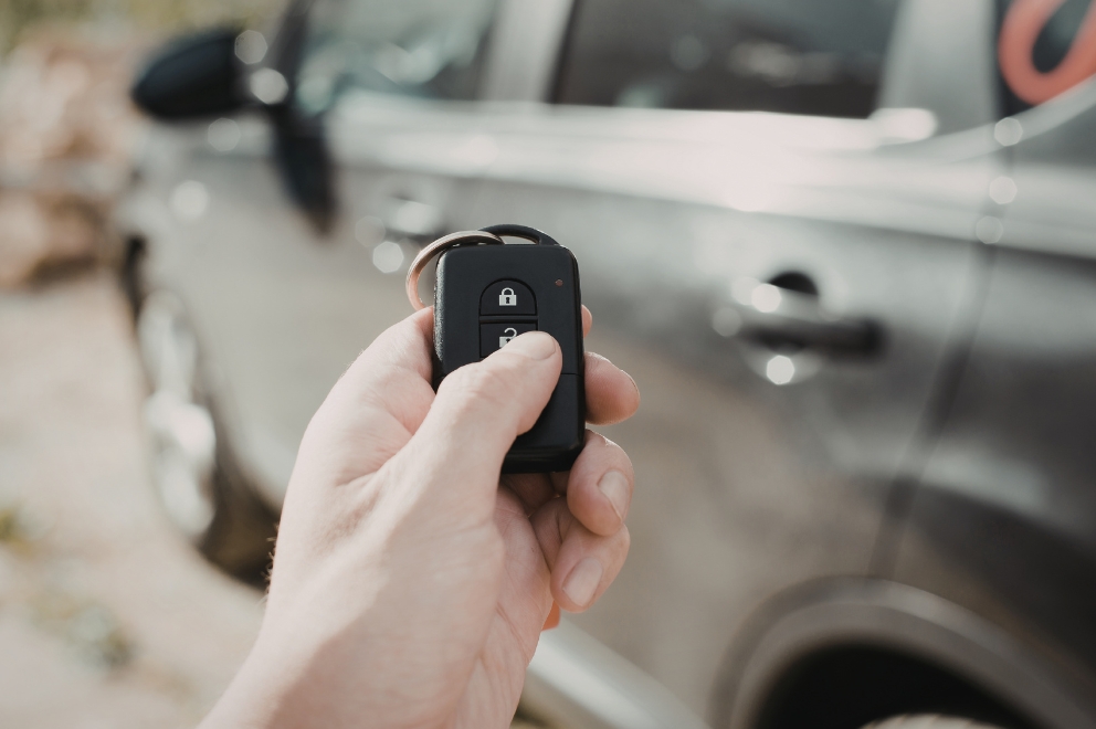 Person holding keychain in front of car